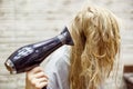 Unidentified blonde woman dries wet hair with Hairdryer