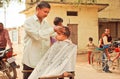 Unidentified boy sitting in chair of rural barber shop and doing new hairstyle by a barber