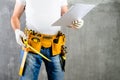 Unidentified builder standing in white gloves with a tool belt w