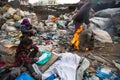 Unidentified child is sitting while her parents are working on dump.