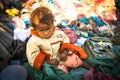 Unidentified child is sitting while her parents are working on dump