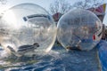 Unidentified children play having fun inside large tarsparent balls on the water