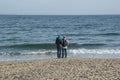 Unidentified couple on the beach looking at the sea in cold weather