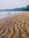 Unidentified couple jogging at beach side during morning hours. Beautiful texture of sea sand