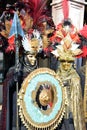 An unidentified couple of man and woman dress elaborate fancy dresses with gold masks, red and black feather hats during Venice Ca