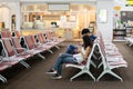 Unidentified couple using cell phone while sitting on chair in lounge zone.