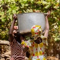 Unidentified Diola women carry a big pan in Kaschouane village.