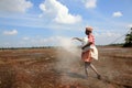 Farm workers plough the wet paddy fields