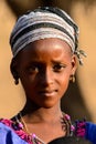 Unidentified Fulani girl in headscarf and colored clothes stand