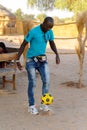 Unidentified Fulani man in jeans and blue shirt plays football