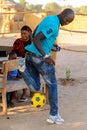 Unidentified Fulani man in jeans and blue shirt plays football