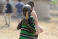 Unidentified Ghanaian boy in striped shirt holds a wooden objec