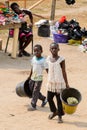 Unidentified Ghanaian kids carry buckets on the street in Elmin