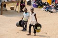 Unidentified Ghanaian kids carry buckets on the street in Elmin