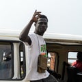 Unidentified Ghanaian man in white shirt raises his hand in Elm