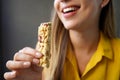 Unidentified girl eating an energetic nuts cereal bar on gray background Royalty Free Stock Photo