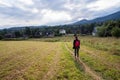 An unidentified girl walking or hiking on a green field in the mountain countryside. Healthy adventure sports and recreation Royalty Free Stock Photo