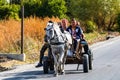 An unidentified group of people on a wagon ride pulled by a white horse. Horse wagon with people on the streets of a village. Royalty Free Stock Photo