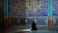 Unidentified Iranian woman wearing chador praying inside Sheikh Lotfollah Mosque with tiles on walls, Isfahan, Iran