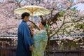 Unidentified Japanese Couple in traditional Kimono dress in a Japanese garden with full bloom cherry