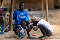 Unidentified local boy cures his friend's foot in a village of