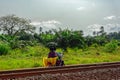 Unidentified local people ride a motorbike on typical red soils Guinea countryside road along railroad of bauxite mining shuttle