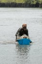 Unidentified local woman pulls a basin along the water in a vil