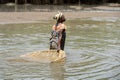 Unidentified local woman pulls a fishing net in the water in a