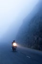 An unidentified male riding motorcycle on the dark misty mountain road, mystic asphalt road in mountain gorge