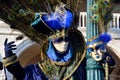 An unidentified man in blue fancy dress with peacock feather on the back keeps a mask in the left hand during Venice Carnival