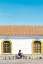 Unidentified man drives a motorbike in front of colonial facade