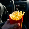 Unidentified man eating French fries while driving a car, close-up