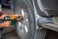 Unidentified man hand making tyre fitting with air compressed wrench screwing up bolts