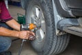 Unidentified man hand making tyre fitting with air compressed wrench screwing up bolts