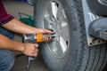 Unidentified man hand making tyre fitting with air compressed wrench screwing up bolts