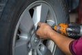 Unidentified man hand making tyre fitting with air compressed wrench screwing up bolts