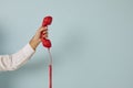 Unidentified man holding red wired retro telephone handset on light blue banner background. Royalty Free Stock Photo