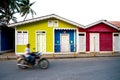 Unidentified man in motion on motorbike passes colorful wooden houses in center of Las Terrenas, Dominican Republic