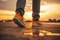 An unidentified man walks in red sneakers on the asphalt towards the sunset. The concept of the big way Royalty Free Stock Photo