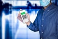 unidentified man wearing a face mask and holding a passport and a Green pass meaningless QR code representing a