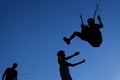 unidentified paraglider in the blue sky landing into a hags of instructor. Training in paraglider school.