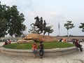 Unidentified people sit and rest by the horse monument to the warriors Techo Meas and Techo Yot at Preah Sisowath Quay riverfront