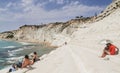 Unidentified peoplel sits on a slope of white cliff called Scala dei Turchi