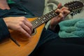 An unidentified person playing mandolin while relaxing on a sofa.