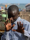 Unidentified Senegalese man in plaid shirt raises his hands on