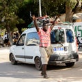 Unidentified Senegalese man in striped shirt raises his hands u