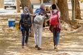 Unidentified Senegalese three women with backpacks walk beside