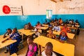 Unidentified serious and sad african children sitting at desks in a classroom in a primary school. New class with new desks, roof Royalty Free Stock Photo