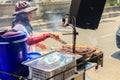 Unidentified street food vendor grilling chicken on smoky oven.