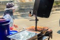 Unidentified street food vendor grilling chicken on smoky oven.